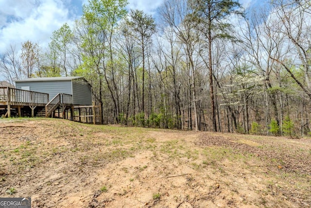 view of yard featuring a forest view and a wooden deck