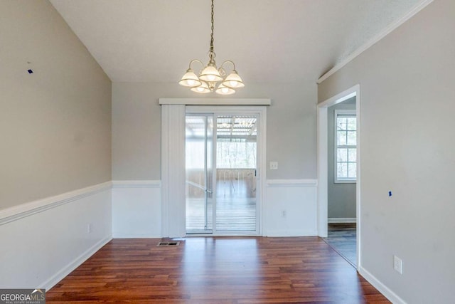 unfurnished dining area featuring baseboards, visible vents, wood finished floors, and an inviting chandelier