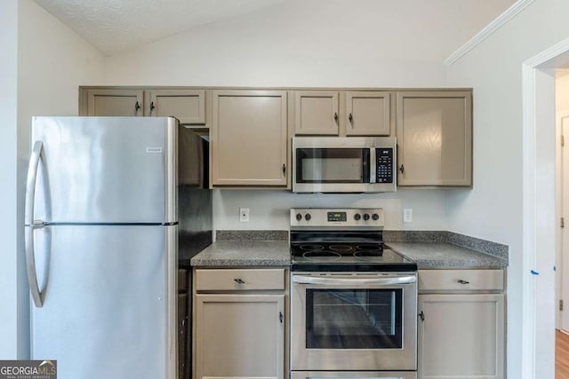 kitchen with dark countertops, stainless steel appliances, vaulted ceiling, and gray cabinets