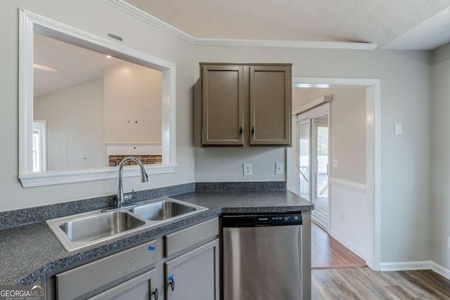 kitchen featuring a sink, stainless steel dishwasher, light wood-style flooring, baseboards, and dark countertops