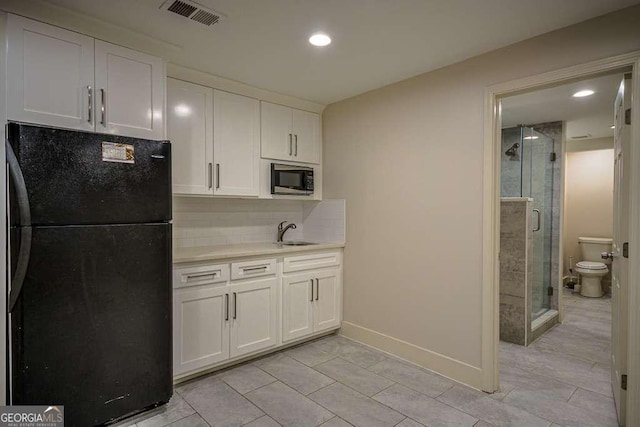 2048 Kelvin Dr, Lawrenceville, GA 30043 - kitchen with freestanding refrigerator, stainless steel microwave, light countertops, tasteful backsplash, and white cabinets