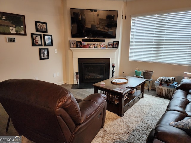 living area with a fireplace with flush hearth, baseboards, and wood finished floors
