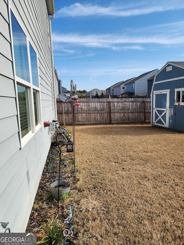 view of yard with a storage shed, a fenced backyard, and an outbuilding