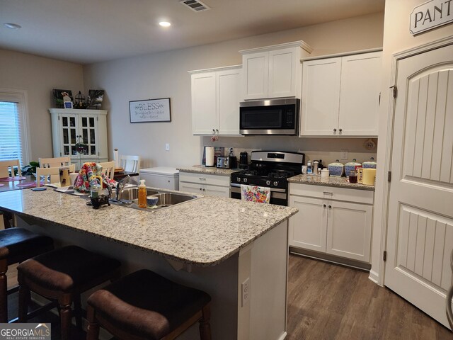 kitchen with stainless steel appliances, white cabinets, a kitchen breakfast bar, and a sink