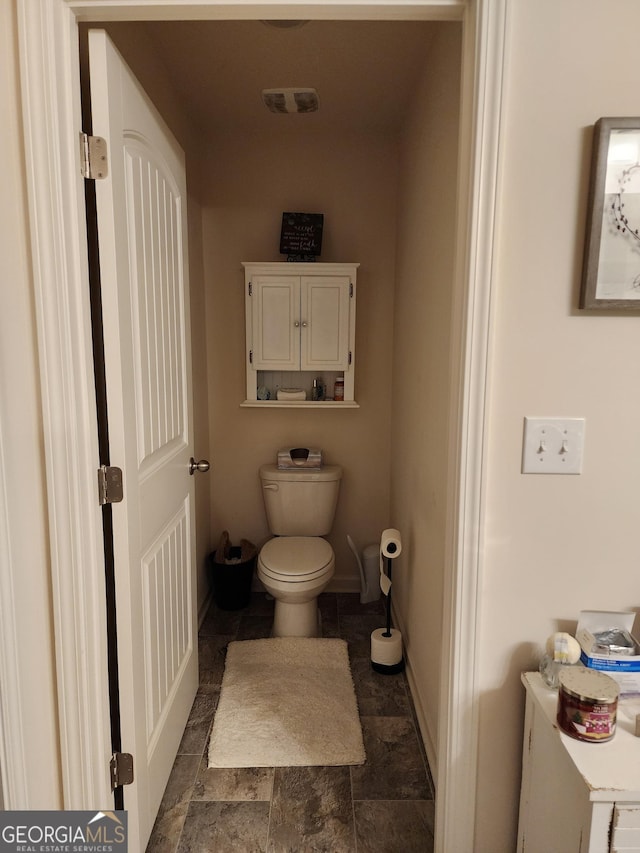 bathroom with visible vents, toilet, baseboards, and stone finish flooring