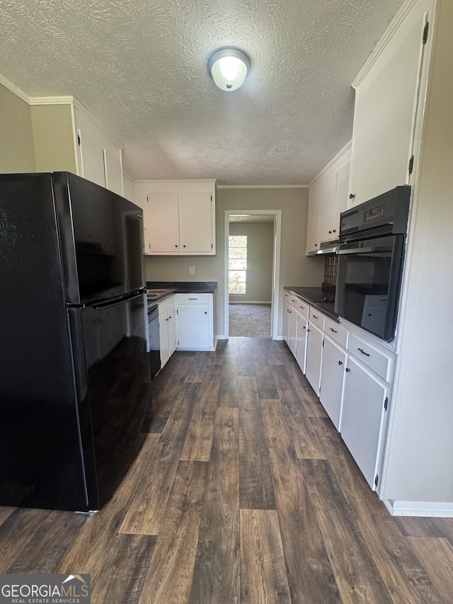 22 Spring Ave, Mcrae-Helena, GA 31055 - kitchen with black appliances, dark wood-type flooring, dark countertops, a textured ceiling, and white cabinetry