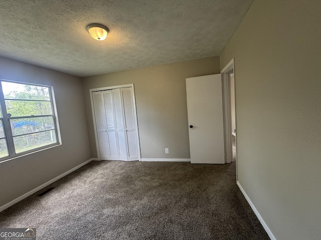 22 Spring Ave, Mcrae-Helena, GA 31055 - unfurnished bedroom with a textured ceiling, dark carpet, and a closet
