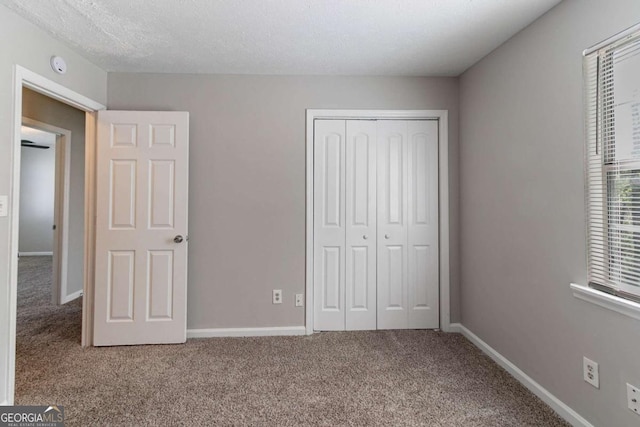 unfurnished bedroom with baseboards, a closet, carpet flooring, and a textured ceiling