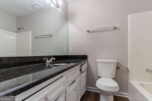 bathroom with toilet, vanity, wood finished floors, baseboards, and visible vents