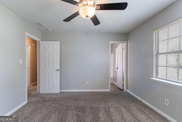 2030 Hilda Burns Pl, Lithonia, GA 30058 - unfurnished bedroom featuring multiple windows, carpet floors, a textured ceiling, and a ceiling fan
