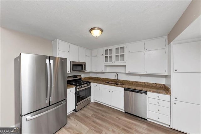 kitchen featuring white cabinets, a sink, light wood-style floors, and appliances with stainless steel finishes