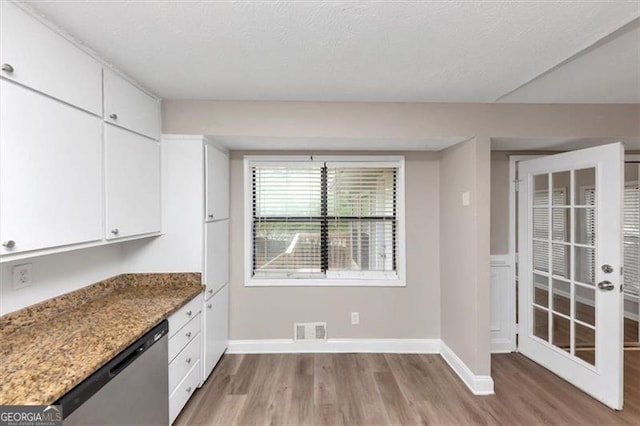kitchen featuring white cabinetry, baseboards, light wood finished floors, visible vents, and dishwasher
