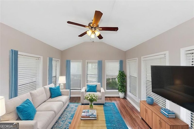 living area with a ceiling fan, baseboards, vaulted ceiling, and wood finished floors