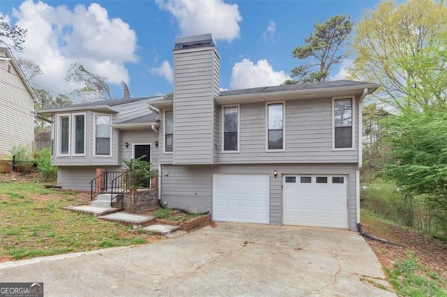 view of front facade featuring an attached garage, a chimney, and concrete driveway
