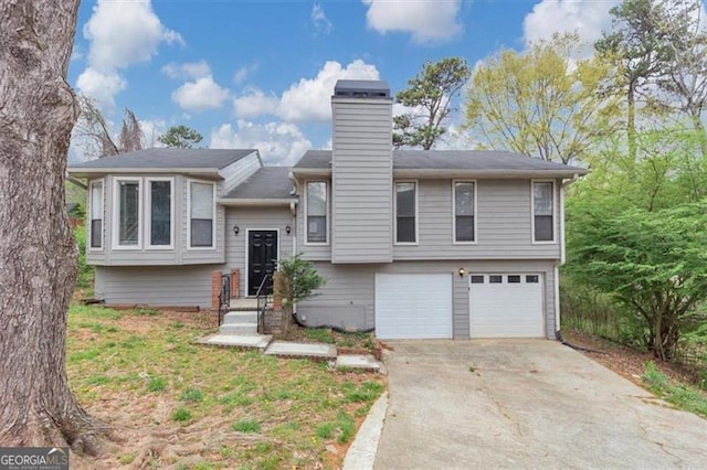 bi-level home with driveway, an attached garage, and a chimney