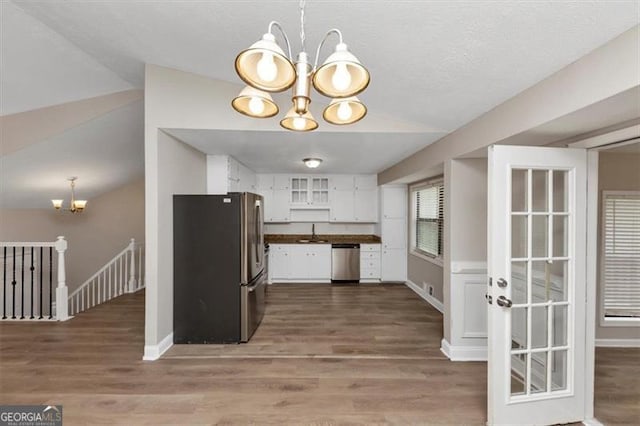 kitchen featuring a sink, white cabinets, a notable chandelier, appliances with stainless steel finishes, and wood finished floors