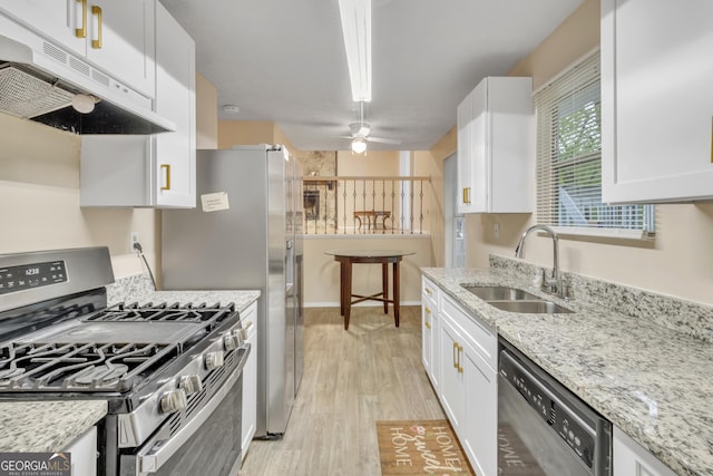 kitchen featuring light wood-style floors, white cabinetry, under cabinet range hood, a sink, and appliances with stainless steel finishes