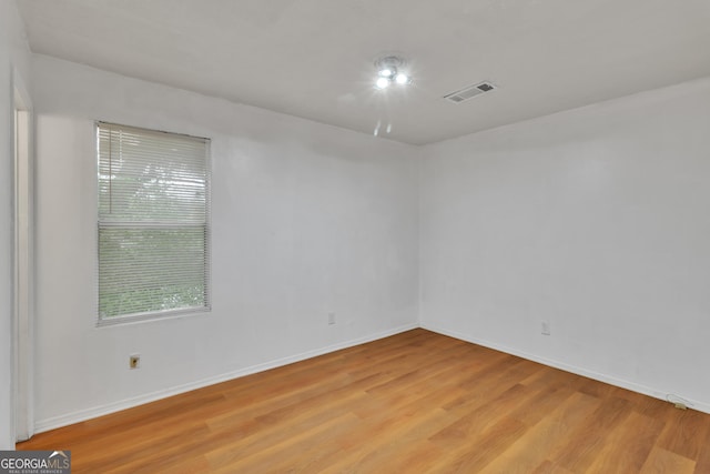 empty room featuring baseboards, light wood-type flooring, and visible vents