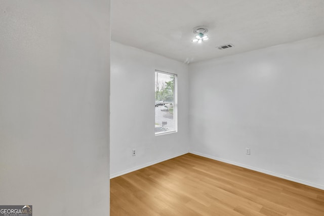unfurnished room featuring baseboards, light wood-style flooring, and visible vents