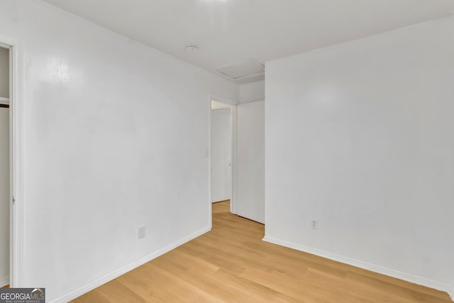 unfurnished room featuring baseboards, attic access, and light wood-style flooring