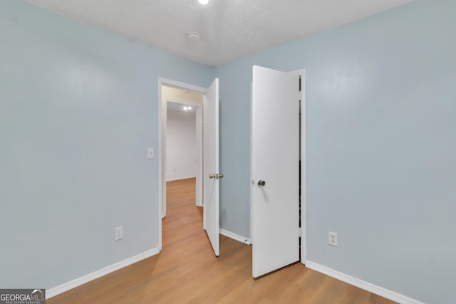 unfurnished bedroom featuring light wood-type flooring, baseboards, and a closet