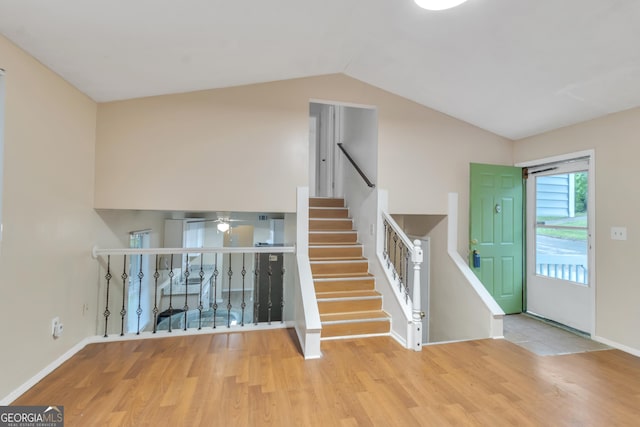 stairs with baseboards, a ceiling fan, wood finished floors, and lofted ceiling