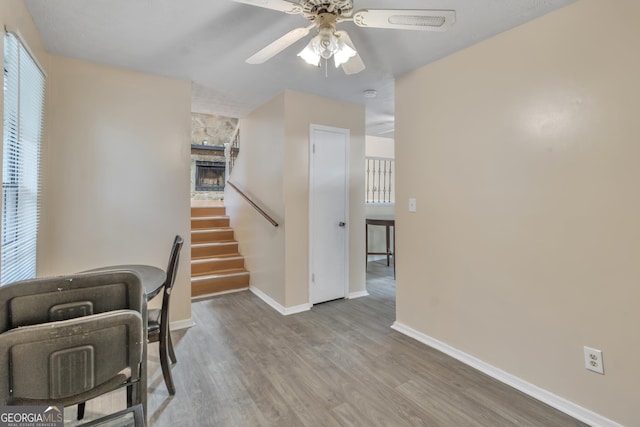 living area featuring stairway, baseboards, a ceiling fan, and wood finished floors