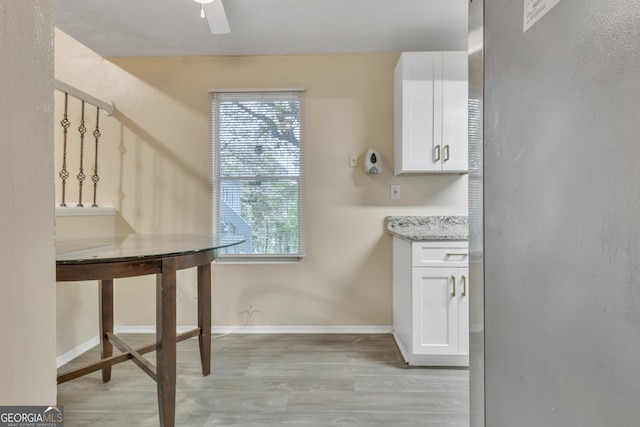 laundry area featuring a healthy amount of sunlight, baseboards, a ceiling fan, and light wood-style flooring