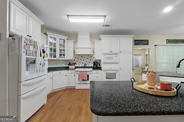 kitchen featuring custom range hood, white appliances, white cabinetry, backsplash, and light wood finished floors
