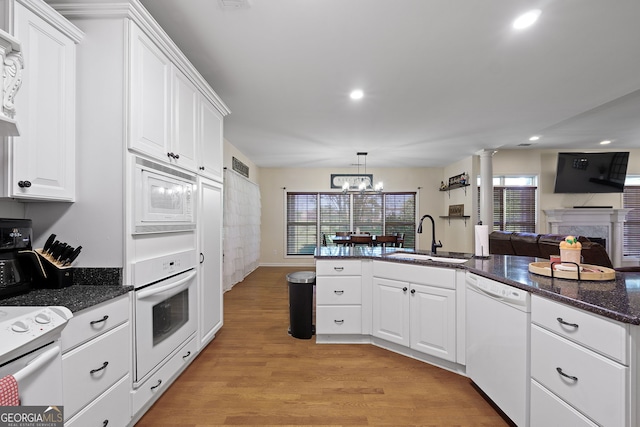 kitchen featuring light wood-type flooring, white appliances, white cabinetry, and a sink