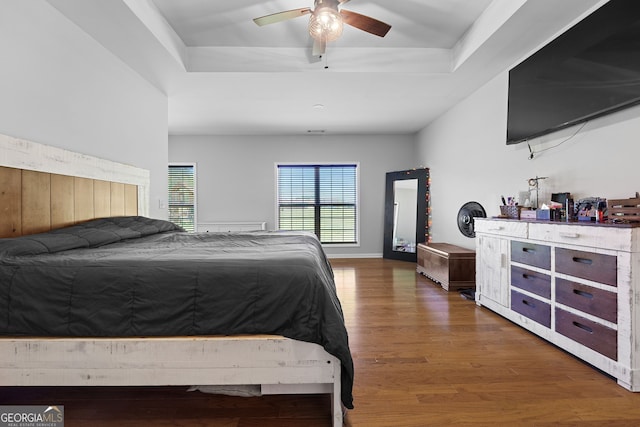 bedroom featuring baseboards, a raised ceiling, ceiling fan, and wood finished floors
