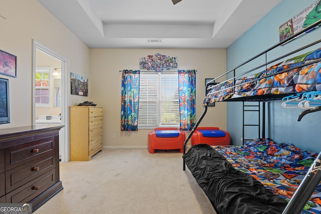 bedroom with a tray ceiling, baseboards, carpet flooring, and visible vents