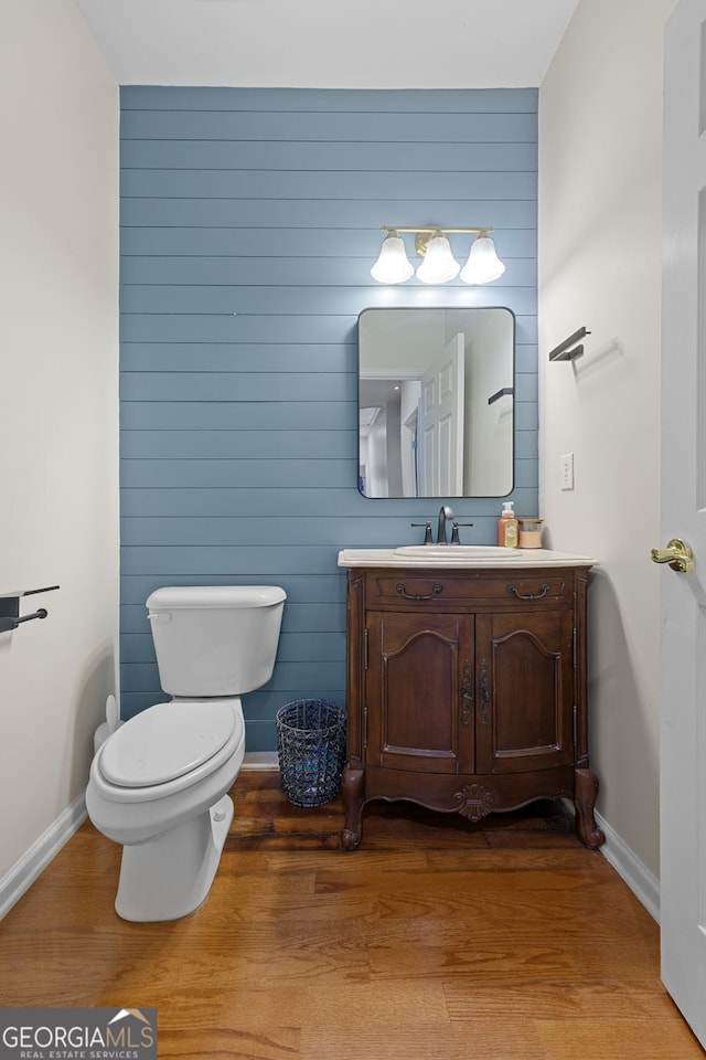 bathroom featuring toilet, wood finished floors, vanity, and baseboards
