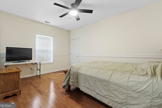 bedroom with wood finished floors, ceiling fan, baseboards, and visible vents