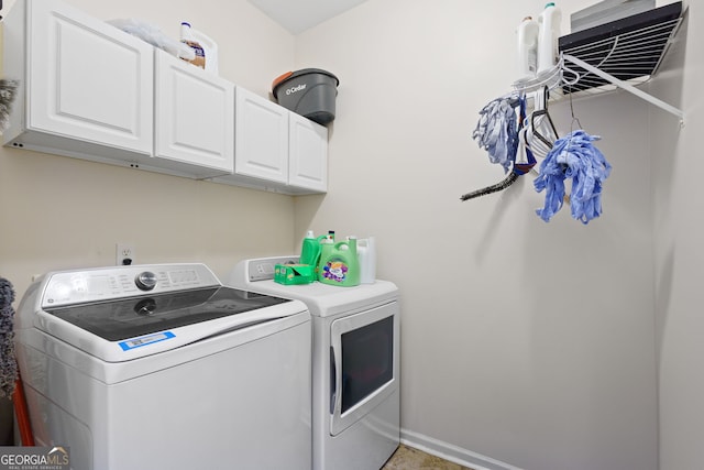 clothes washing area with separate washer and dryer, baseboards, and cabinet space