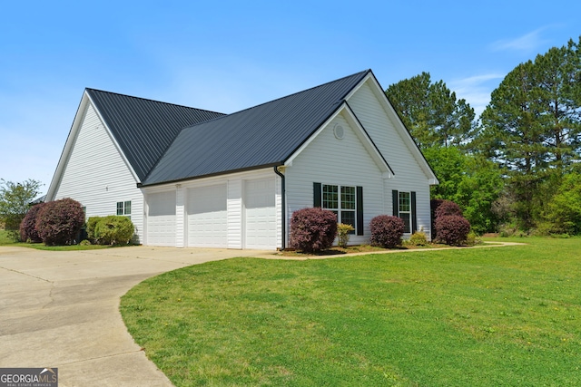 view of side of property with concrete driveway, metal roof, and a lawn