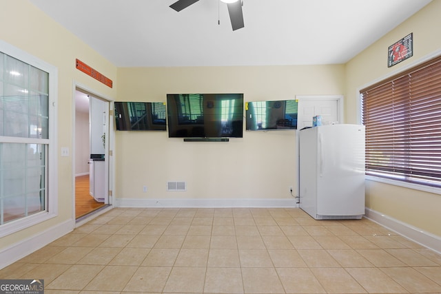 empty room featuring tile patterned flooring, visible vents, baseboards, and ceiling fan