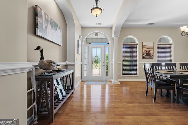foyer entrance featuring decorative columns, visible vents, and wood finished floors