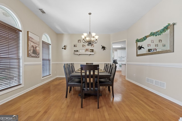 dining area with light wood-style flooring, an inviting chandelier, baseboards, and visible vents