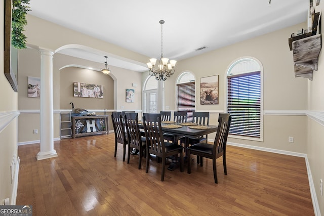 dining area featuring visible vents, baseboards, arched walkways, decorative columns, and wood finished floors