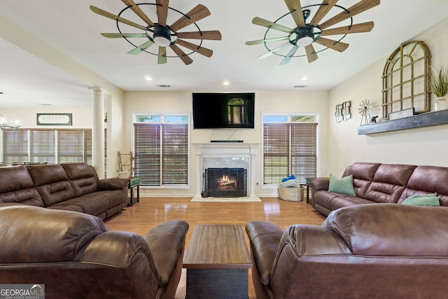 living area with wood finished floors, a high end fireplace, a ceiling fan, and recessed lighting