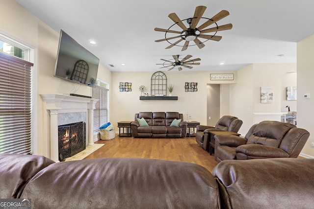 living area with recessed lighting, a wealth of natural light, wood finished floors, ceiling fan, and a premium fireplace