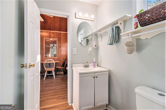half bathroom with toilet, vanity, and wood finished floors