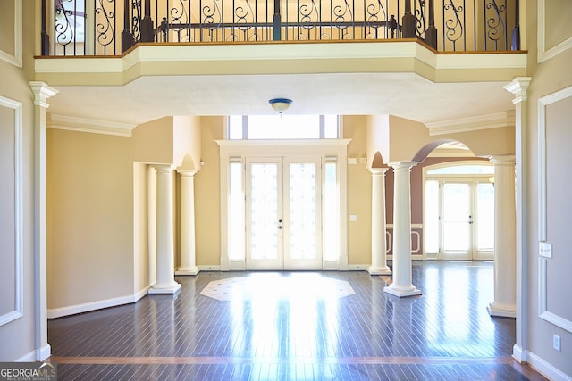 foyer entrance featuring french doors, arched walkways, decorative columns, and dark wood finished floors