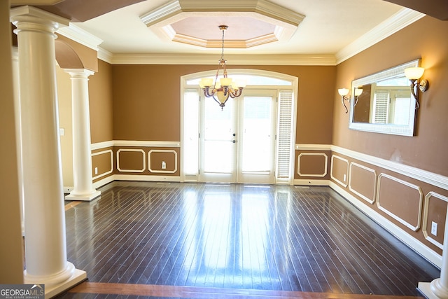 empty room with ornate columns, a healthy amount of sunlight, and dark wood-type flooring