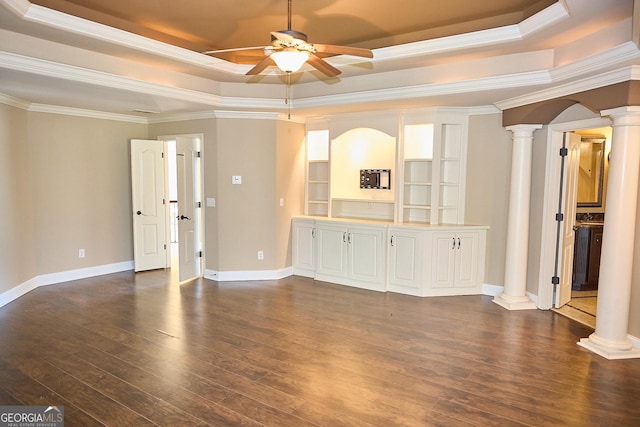 unfurnished living room featuring ornate columns, ceiling fan, a tray ceiling, and dark wood-style floors