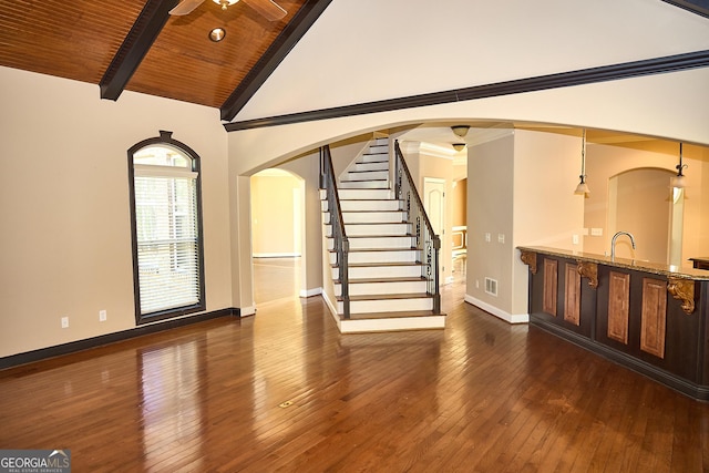 unfurnished living room featuring baseboards, ceiling fan, dark wood-style floors, wood ceiling, and arched walkways