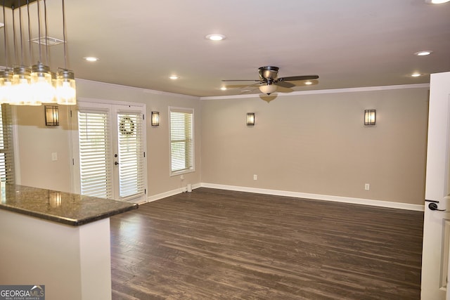 unfurnished living room featuring crown molding, ceiling fan, dark wood finished floors, and baseboards