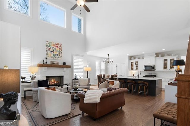 9 Grove Pointe Way, Cartersville, GA 30120 - living area with a ceiling fan, dark wood-style floors, a brick fireplace, a towering ceiling, and a chandelier