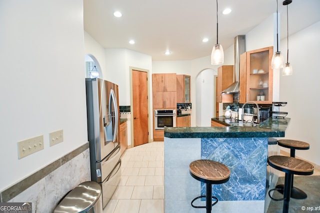 412 Trilium Trl, Pendergrass, GA 30567 - kitchen featuring stainless steel appliances, arched walkways, a peninsula, ventilation hood, and dark countertops